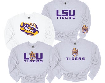 May include: Four crewneck sweatshirts in white and light gray. One features a purple and gold tiger eye graphic. Another displays purple text reading LSU TIGERS with a small tiger head on the sleeve. Two others feature a tiger head with purple text.
