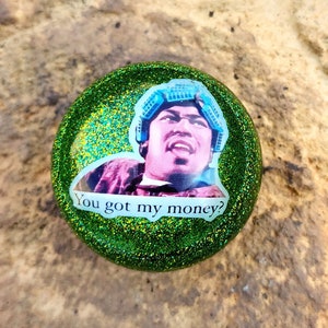 May include: A green glitter resin cabochon with a picture of a man with the text "You got my money?"