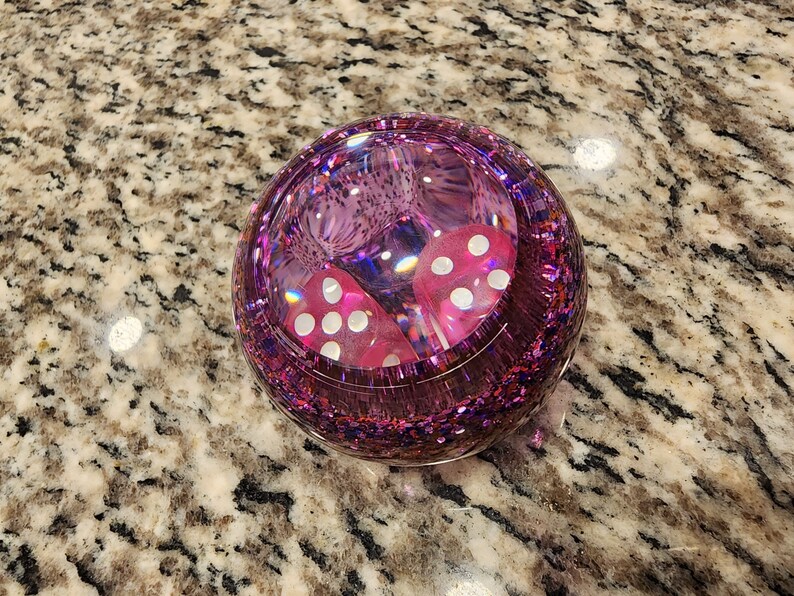 May include: A pink glitter sphere paperweight with two white dice inside.
