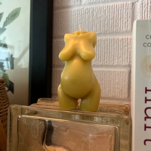 Beeswax candle in the form of a pregnant woman with huge belly is unlit on a birth altar, surrounded by labor books and 4th trimester support. white wick, tan skin candle