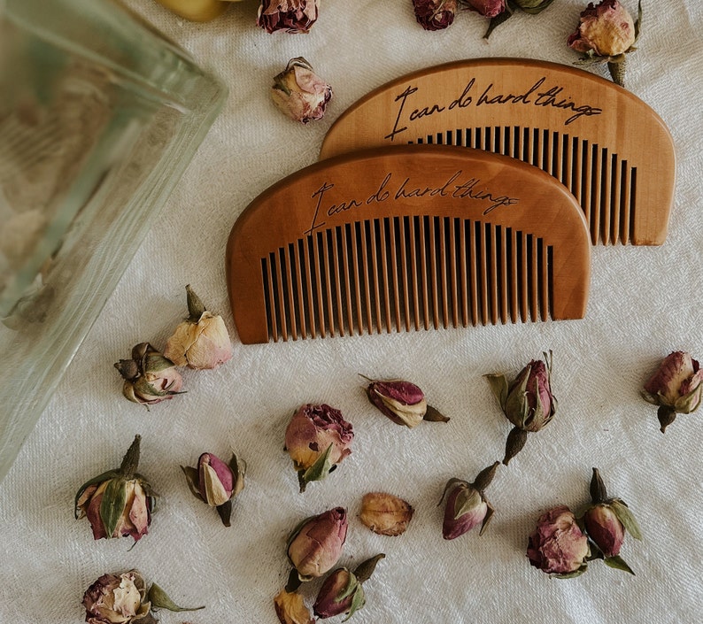 Two small brown hand held wooden comb for natural childbirth and natural pain relief.Dried rose buds scattered on birth alter on a white cloth