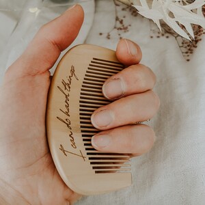 Natural birth comb held in mother's hand displaying the saying I can do hard things lifted up above a birth alter with fairy lights dried flowers and a neutral blanket