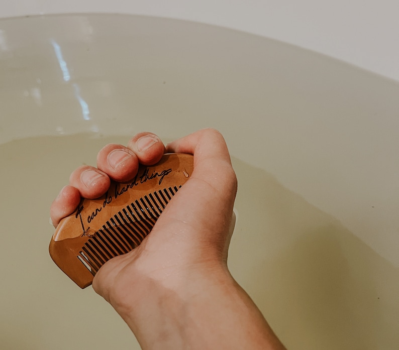 Mother holding wooden birth comb in a tub, gripping for natural pain relief with the affirmation I can do hard things.