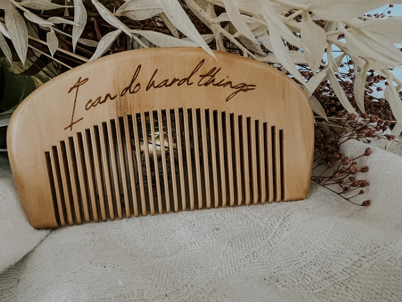Tan labor comb with I can do hard things engraved. Small comb for hand held during birth. Resting in front of dried sage and flowers