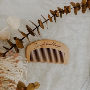 Small hand held wooden comb for natural childbirth and natural pain relief. Birth comb says "I can do hard things". On a birth alterwith dried flowers and affirmation cards