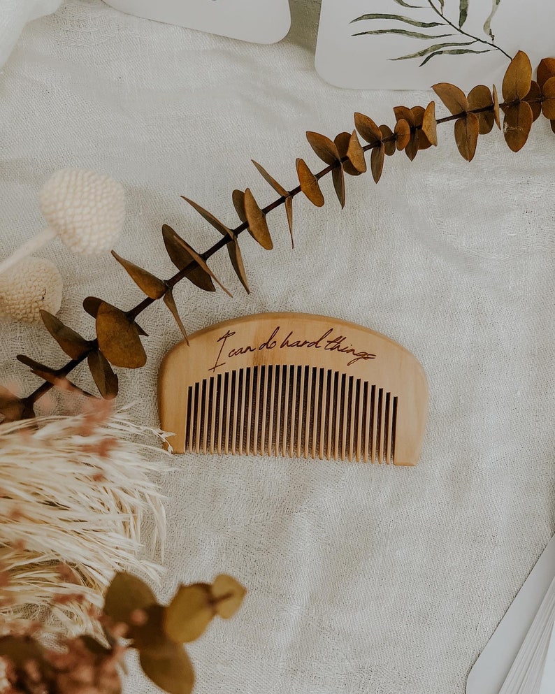 Small hand held wooden comb for natural childbirth and natural pain relief. Birth comb says "I can do hard things". On a birth alterwith dried flowers and affirmation cards