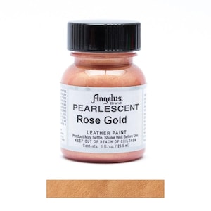 Può includere: Una bottiglia di vernice per pelle Angelus Pearlescent Rose Gold. La bottiglia ha un tappo nero e un'etichetta con il nome e il marchio del prodotto. La vernice è di colore oro rosa metallizzato. Sotto la bottiglia è mostrata una campionatura della vernice.