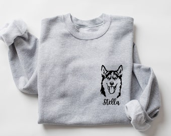 Op de afbeelding: Grijs sweatshirt met een zwart-witte illustratie van een husky-hondenkop en de naam "Stella" gedrukt op de voorkant.