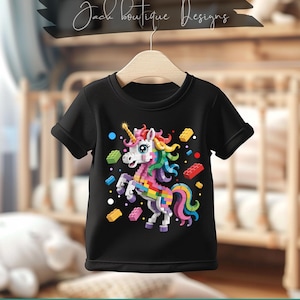 Peut inclure: T-shirt noir avec un motif de licorne colorée fait de blocs de construction. La licorne a une corne dorée, une crinière rose et une queue arc-en-ciel. Le t-shirt porte également le texte "Jack boutique Designs" et "PNG. SVG. PDF. 300 DPI".