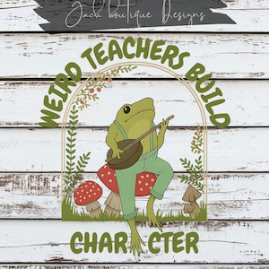 Peut inclure: Un design fantaisiste avec une grenouille verte jouant du banjo, assise sur un champignon rouge à pois blancs. Le texte dit "Weird Teachers Build Character" en cercle. Le design est sur un fond en bois blanc.