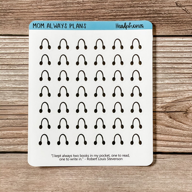 May include: A sheet of white sticker paper with 36 black headphone stickers. The stickers are arranged in 6 rows of 6. The sheet has the text "MOM ALWAYS PLANS" and "Headphones" at the top. The bottom of the sheet has a quote by Robert Louis Stevenson: "I kept always two books in my pocket, one to read, one to write in."