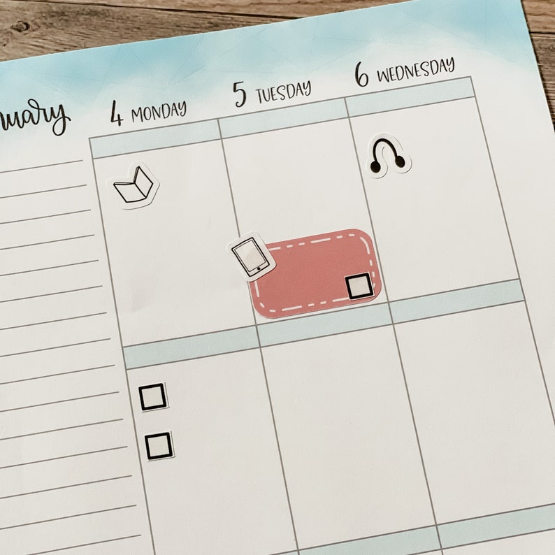 May include: A weekly planner with a light blue background and white grid lines. The days of the week are labeled at the top of each column. The days of the week are Monday, Tuesday, Wednesday. There are stickers on the planner, including a book, a phone, headphones, and a check box.