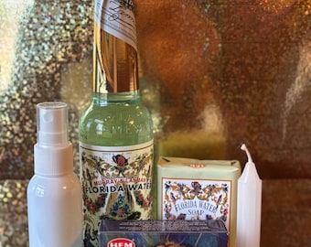 May include: A set of items for a money attraction ritual, including a bottle of Florida Water, a white spray bottle, a white candle, and a box of incense cones with the text "Attracts Money" and a picture of hands holding coins.