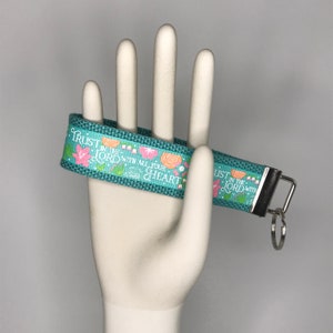 May include: A teal blue key chain with a floral design and the text "Trust in the Lord with all your heart" and "Trust in the Lord with all your heart".