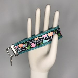May include: Teal blue key chain with a floral design and the text "Trust in the Lord with all your heart".