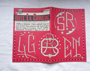 Peut inclure: Un livret rouge avec le titre "TOUTE LA BRODERIE" et le texte "ALBUM PROFESSIONNEL POUR LE TROUSSEAU". Le livret présente plusieurs motifs de broderie, notamment les lettres "SR", "LG" et "RB".