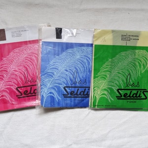 May include: Three packs of tights featuring a feather design and the text "Bras Seldi's" in black. The packs are pink, blue and green.