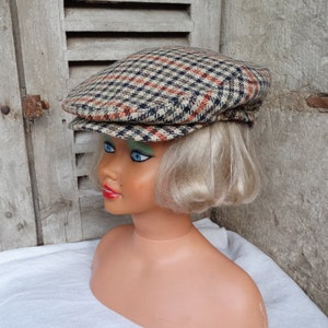 May include: A brown, black, and red plaid newsboy cap with a flat top and a curved brim.
