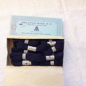 May include: A box of navy blue embroidery floss with the label "DOLLFUS-MIEG & C SOCIETE ANONYME MULHOUSE-BELFORT-PARIS" and the DMC logo.
