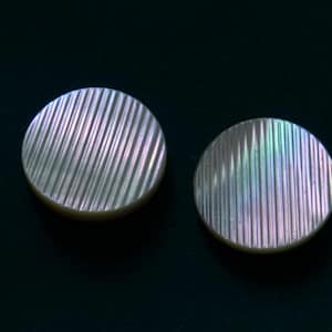 Peut inclure: Deux boutons en nacre blanche irisée avec un motif rayé.