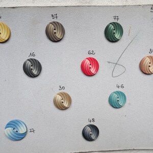 May include: A collection of decorative buttons in various colors, including yellow, gray, green, red, and blue. Each button has a spiral design and two holes for sewing. Numbers are printed next to each button. The number "5890 1/86" is printed in the upper right corner.