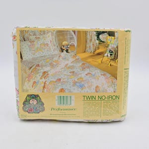 May include: A packaged twin-size, no-iron bed sheet set featuring a Cabbage Patch Kids design. The packaging displays a bed with a floral pattern and Cabbage Patch Kids dolls. The set includes pillowcases, and the packaging has a barcode.