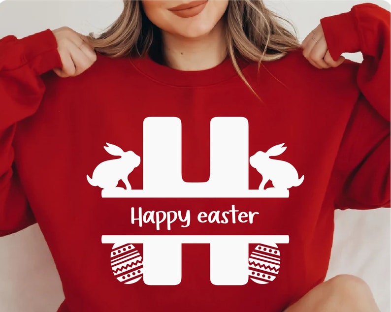 Puede incluir: Sudadera roja con una letra H blanca, dos conejos blancos y el texto "Happy easter" en la parte delantera.