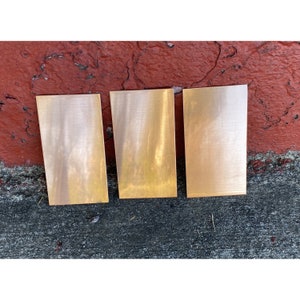 May include: Three rectangular pieces of polished copper metal.