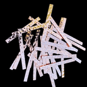 May include: A pile of hammered metal strips in shades of gold and silver. The strips are arranged in a random pattern, creating a textured and abstract design.