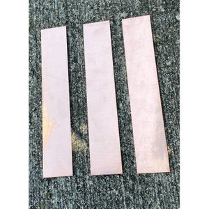 May include: Three rectangular pieces of copper sheet metal. The sheets are a light pink color and have a slightly textured surface.