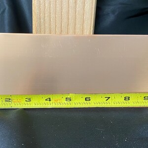 May include: A copper sheet measuring 9 inches by 4 inches. The sheet is a light copper color and has a smooth, slightly textured surface.
