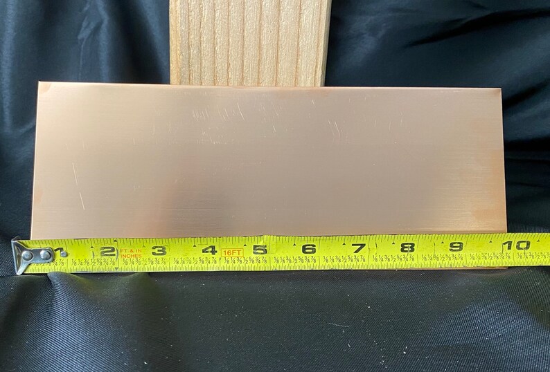 May include: A copper sheet measuring 9 inches by 4 inches. The sheet is a light copper color and has a smooth, slightly textured surface.