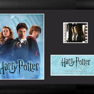 May include: A framed movie poster and film cell from the movie Harry Potter and the Half-Blood Prince. The poster features Harry Potter, Ron Weasley, and Hermione Granger. The film cell shows a scene from the movie.