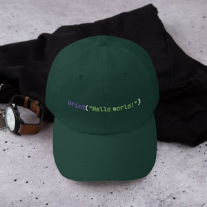 May include: A dark green baseball cap with the code "print("Hello world!")" embroidered in purple and green on the front.