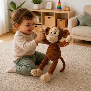 Pode incluir: Um bicho de pelúcia de macaco feito em crochê nas cores marrom e creme, com rosto redondo, olhos escuros e um sorriso bordado. O brinquedo apresenta braços e pernas longos com mãos e pés na cor creme, uma cauda longa e textura de fio.