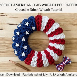 May include: A crocheted wreath in the style of the American flag, featuring blue sections with white stars and red and white stripes. The text "CROCHET AMERICAN FLAG WREATH PDF PATTERN" is at the top. A crochet hook and yarn are also visible.