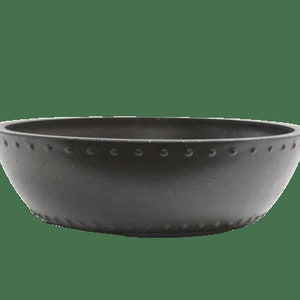 May include: A dark gray, round bowl with a wide rim. The rim is decorated with evenly spaced, small, circular indentations. The bowl has a slightly flared shape and a smooth, matte finish. The bowl is likely made of ceramic or a similar material.
