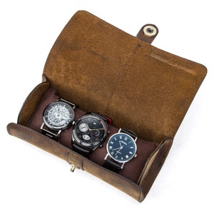 Peut inclure: Un porte-montres en cuir marron avec trois montres &agrave; l'int&eacute;rieur. Les montres ont des styles et des designs diff&eacute;rents.