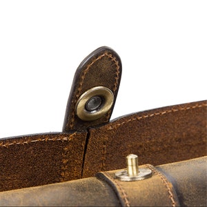 Peut inclure: Gros plan sur un sac en cuir marron avec une fermeture &agrave; pression en m&eacute;tal. Le sac a un aspect vieilli et est fait de cuir de haute qualit&eacute;.