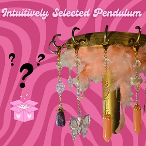 May include: A selection of intuitively selected pendulums hang from a gold-colored stand with pink feathers. The pendulums feature various crystal and gemstone designs, including a butterfly, and a purple stone. The background is a pink and white swirled pattern.