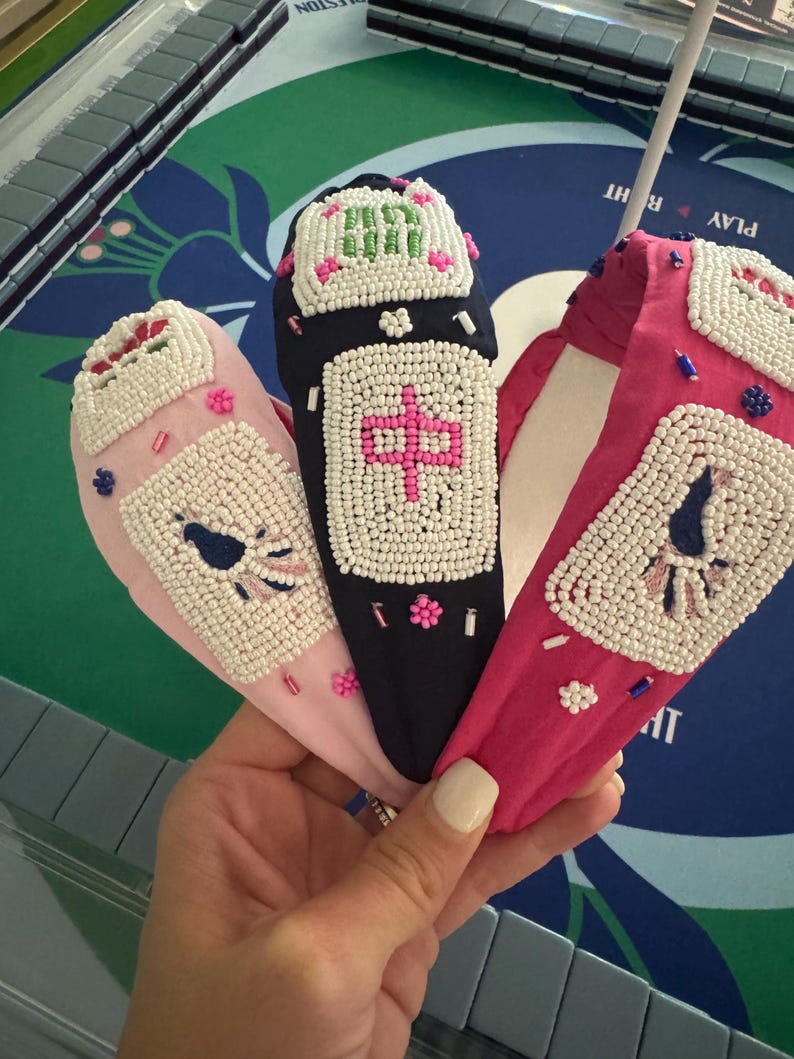 Puede incluir: Tres diademas con cuentas en rosa, negro y fucsia. Cada diadema presenta un dise&ntilde;o central con cuentas blancas y detalles coloridos. La diadema negra tiene un car&aacute;cter chino. Las diademas rosa y fucsia tienen otros dise&ntilde;os.