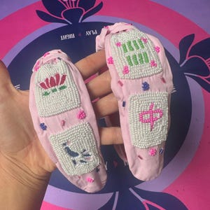 Puede incluir: Diademas de tela rosa con dise&ntilde;os de cuentas. Una diadema presenta una flor de loto, la otra un p&aacute;jaro. Las otras dos diademas tienen caracteres y s&iacute;mbolos chinos. Las diademas est&aacute;n decoradas con cuentas rosas, verdes y azules.