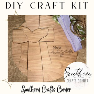 May include: DIY craft kit featuring a wooden round sign with a cross and dove design. The sign is engraved with the words "He is risen". The kit includes a green and white checkered ribbon, a purple ribbon, and a brown twine.