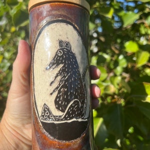 May include: A cylindrical ceramic container with a bamboo lid. The container features a black and white illustration of a rat within an oval frame. The ceramic has a brown and iridescent glaze.