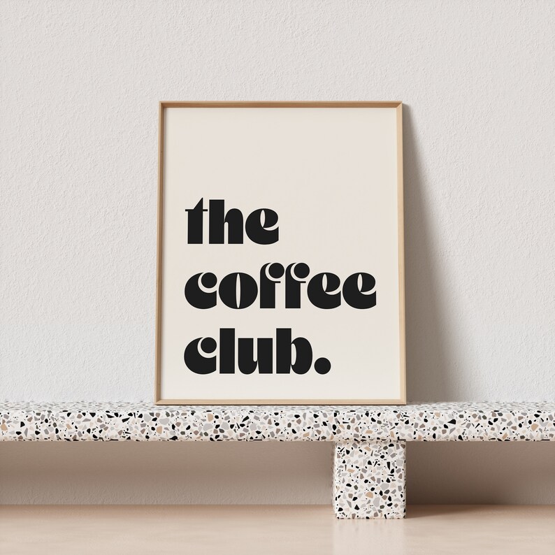 May include: A framed print with the text "the coffee club." in black bold letters on a white background.