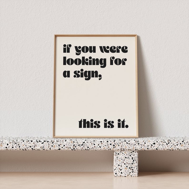 May include: A framed print with a beige background and black text that reads "if you were looking for a sign, this is it."