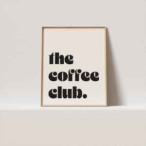 May include: A framed print with the text "the coffee club" in a bold, black font on a white background.