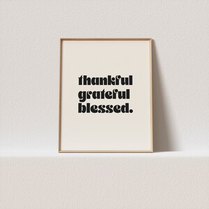 Könnte beinhalten: Ein gerahmter Druck mit dem Text "thankful grateful blessed." in schwarzen Fettdruck auf weißem Hintergrund.