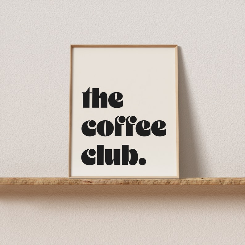 May include: A framed print with the text "the coffee club." in black bold letters on a white background.