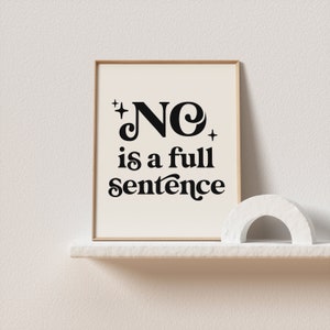 May include: A framed print with the words "NO is a full sentence" in black, stylized font. The print is on a cream-colored background and has a gold frame. A white, arched sculpture sits on a shelf below the print.